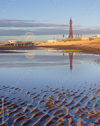 Blackpool promenade viewed from the beach with the tower and the central pier`s big wheel reflected in water