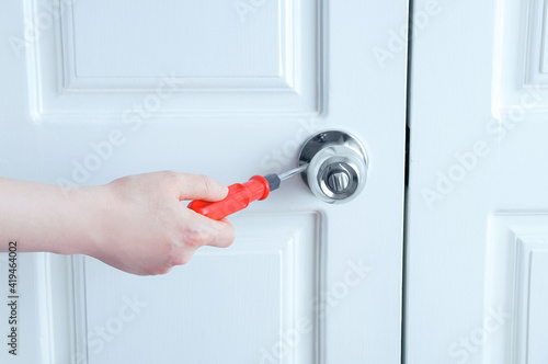 Close-up hand is screwing  door handle with a screwdriver. © Iuliia Alekseeva