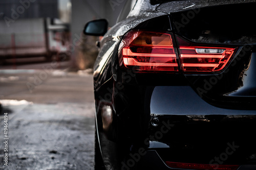 A view of the rear light of a luxury black sports car.