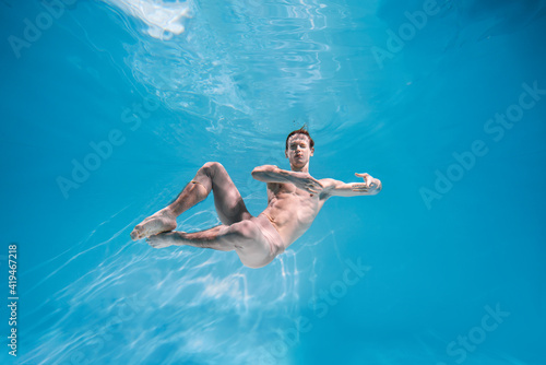 Male Caucasian man swimmer diver dancer swims under water in the sea. Summer tourism, travel journey trip voyage, holiday and vacation. Concertation, art, beauty and freedom concept