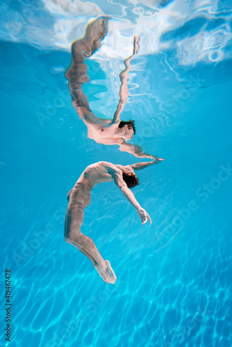 Male Caucasian man swimmer diver dancer swims under water in the sea. Summer tourism  travel journey trip voyage  holiday and vacation. Concertation  art  beauty and freedom concept