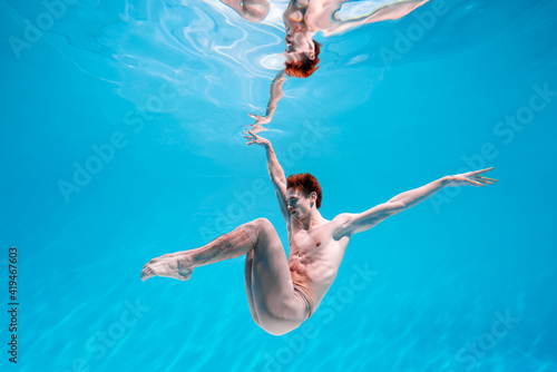 Male Caucasian man swimmer diver dancer swims under water in the sea. Summer tourism, travel journey trip voyage, holiday and vacation. Concertation, art, beauty and freedom concept