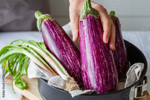 Crop anonymous person preparing vegetable for cooking healthy lunch with green onion in kitchen photo