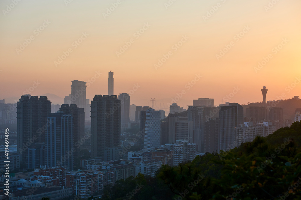 Peaceful view of contemporary metropolis with skyscrapers and residential buildings under orange sky in twilight Peaceful view of contemporary metropolis with skyscrapers and residential buildings under orange sky in twilight