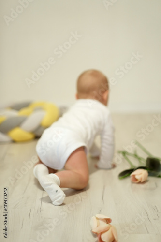 Abstract blurred background with selective focus. Baby crawls away from the camera, view from the back, focus on the heels