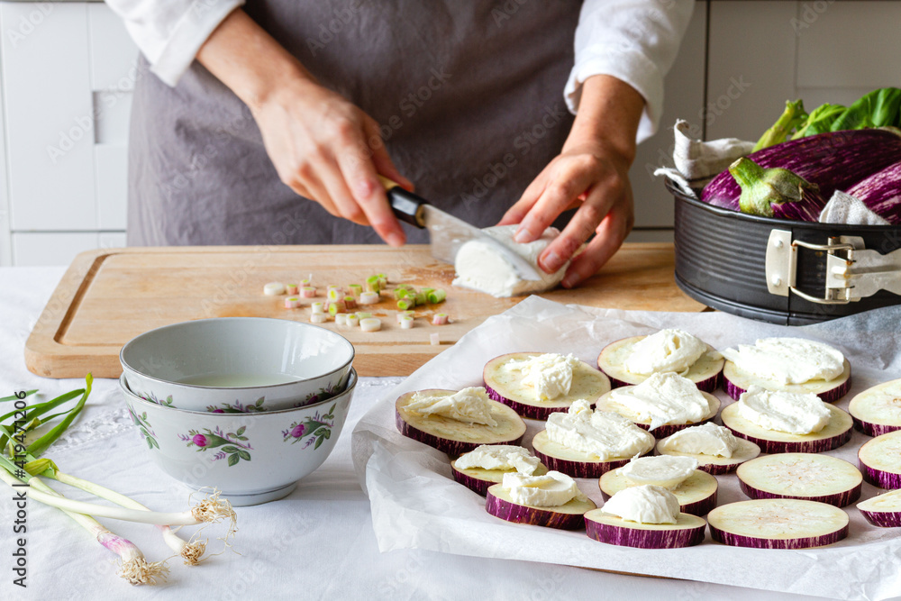 Crop unrecognizable cook preparing cheese for cooking eggplant appetizers with green onion at home Crop unrecognizable cook preparing cheese for cooking eggplant appetizers with green onion at home