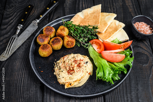 Arabic cuisine Hummus chickpea  falafel  pita bread and fresh vegetables. Black wooden background. Top view