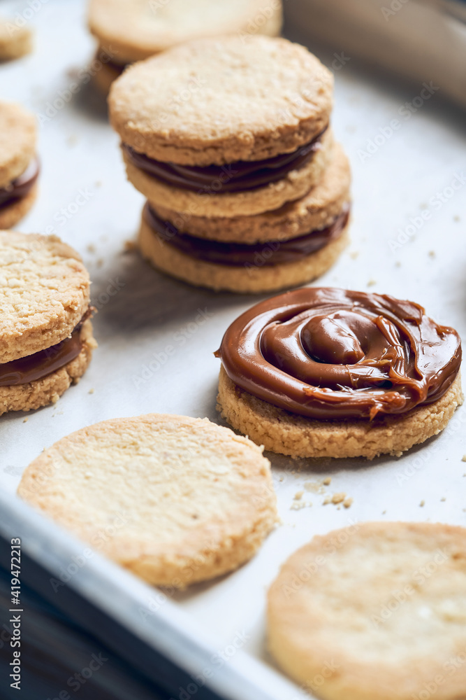 High angle of sweet sandwich cookies with cream caramel stuffing placed on metal tray High angle of sweet sandwich cookies with cream caramel stuffing placed on metal tray