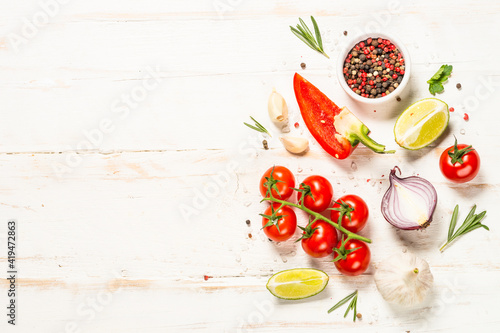 Food cooking background on white wooden table. Fresh vegetables, spices, herbs and oil. Ingredients for cooking. Top view with copy space.