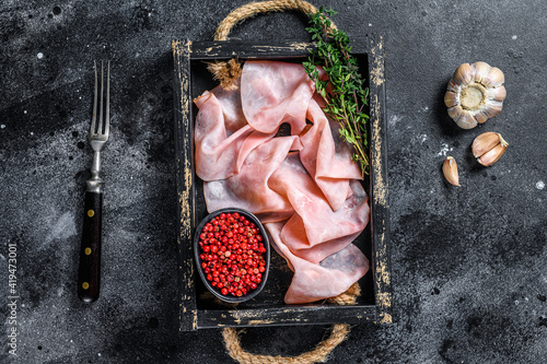 Thin sliced Smoked  pork ham in wooden tray. Black background. Top view photo