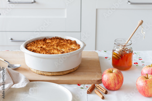 Honey and apples with cinnamon placed near baking pan with delicious crumble in kitchen at home photo