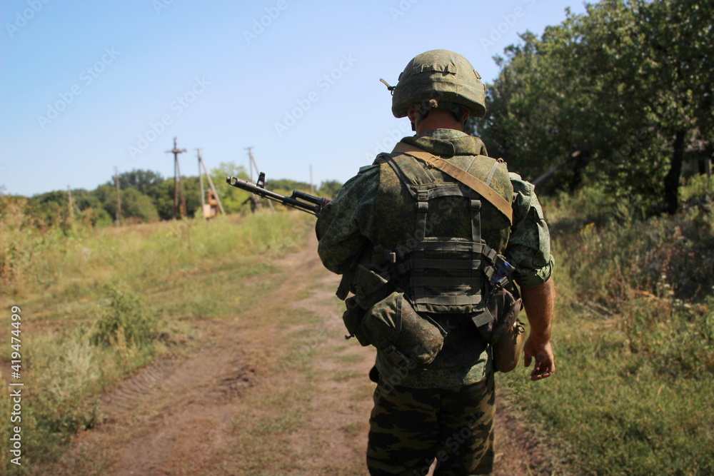 A soldier with a assault rifle and body armor on a blurred background. Automatic weapons. A soldier with a assault rifle and body armor on a blurred background. Automatic weapons.