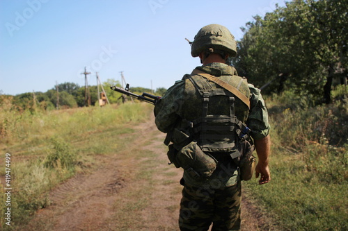 A soldier with a assault rifle and body armor on a blurred background. Automatic weapons.
