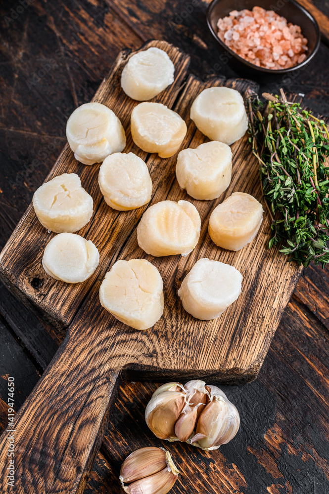 Steamed scallops meat on a wooden board. Dark wooden background. Top view