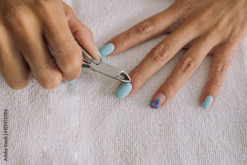 From above of crop unrecognizable young female cutting cuticles with nipper in beauty salon photo