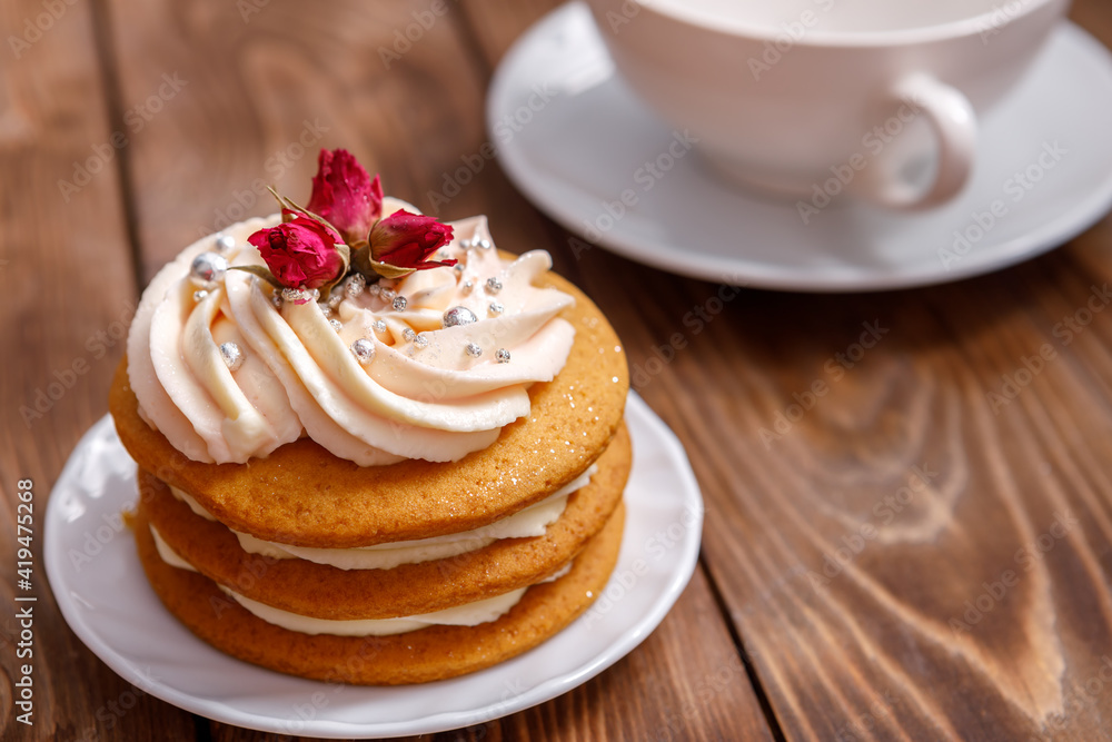 Sponge cake with cream, decorated with small flowers and a cup of tea. Sponge cake with cream, decorated with small flowers and a cup of tea.