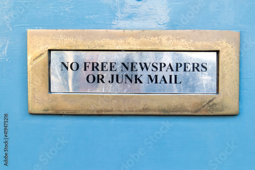 House letterbox with 'No junk mail' sign and junk mail © elenarostunova