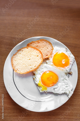 An omelet of chicken eggs, freshly made, is on a plate and two slices of white bread.