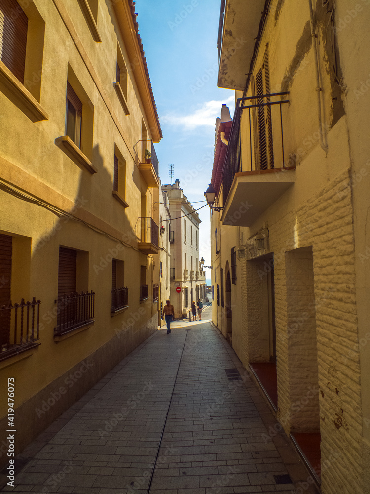 Obraz premium Calle estrecha con fachadas encaladas que parecen de color dorado por el sol del atardecer