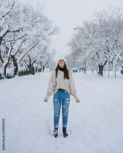 Young happy female standing on winter snow park with white trees in Madrid with eyes closed photo