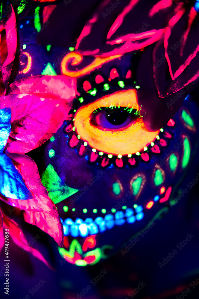Anonymous female in multicolored masquerade mask with flowers on head looking at camera on Halloween night Anonymous female in multicolored masquerade mask with flowers on head looking at camera on Halloween night