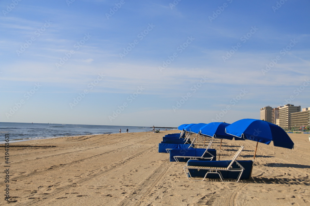 row of blue umbrella beaches lined up in the sandy beaches of Virginia