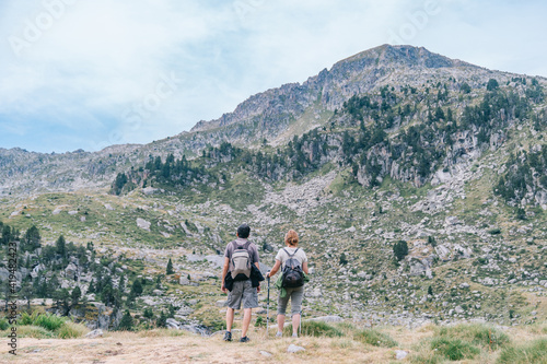 Back view of anonymous backpackers walking on mountain during summer trip photo