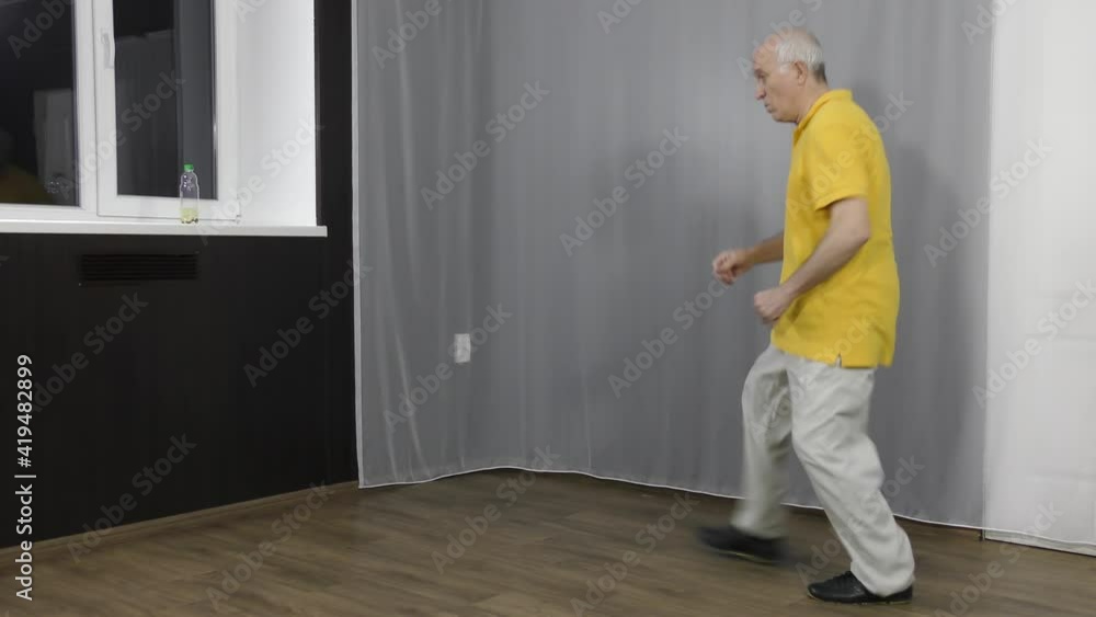 Old man athlete training squats with bounces by the window Old man athlete training squats with bounces by the window