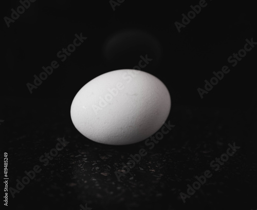 The egg is white, against a black background. Selective focus.