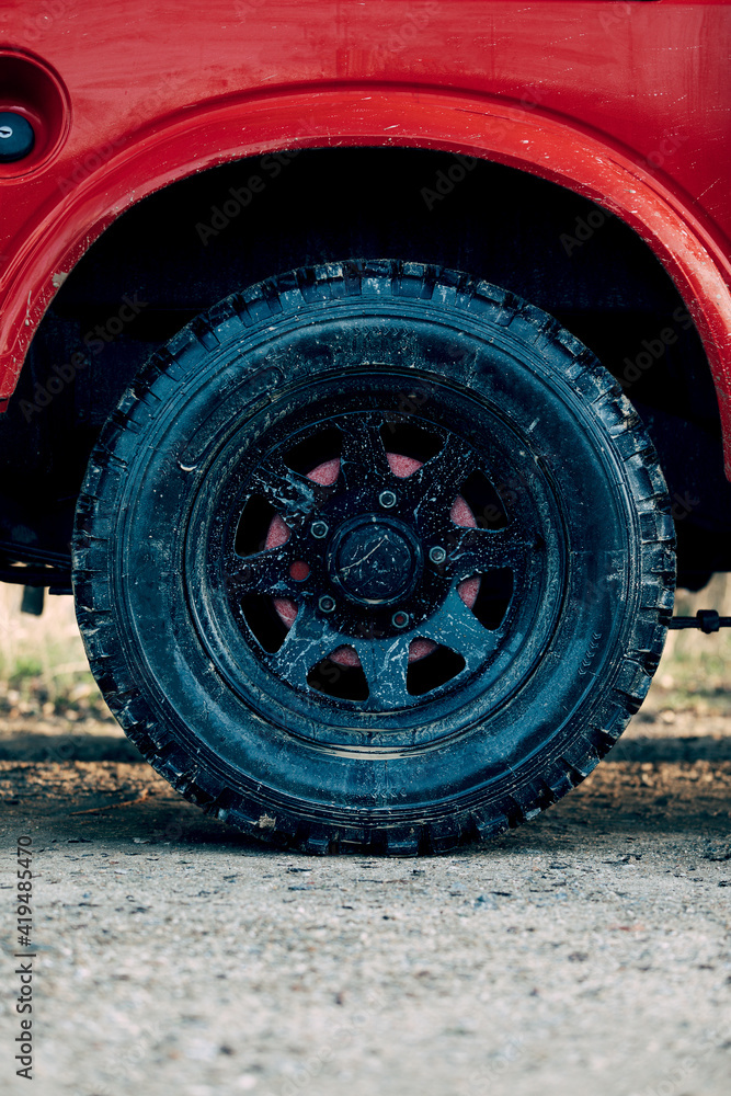 Red SUV vehicle with black wheel tires parked on dirt road during adventure in countryside Red SUV vehicle with black wheel tires parked on dirt road during adventure in countryside