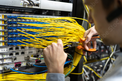 Crop male technician with wire cutters working with electronic system of server room