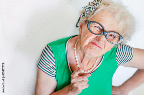 Photo Stylish emotional elderly woman with an evil face waving index finger over white background