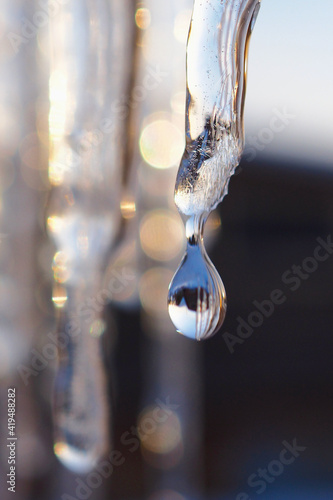 Tela An icicle and a drop of meltwater in the rays of the sunset close-up