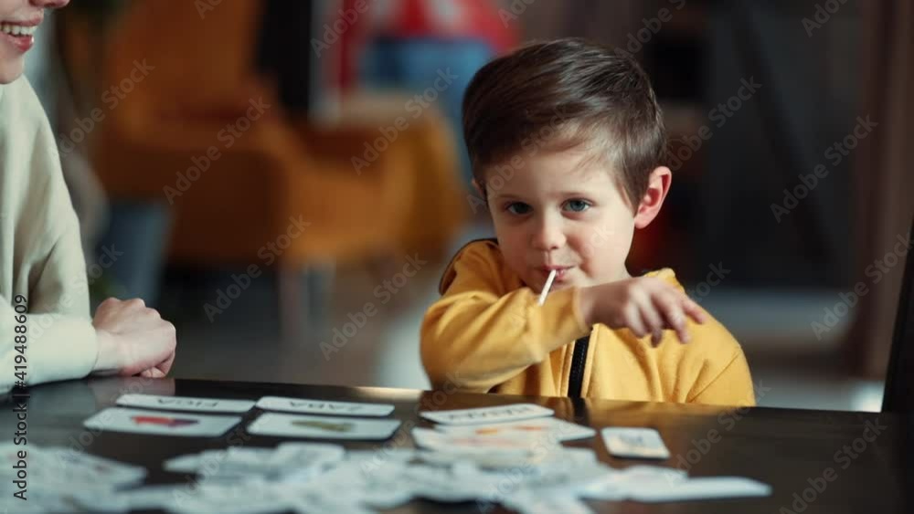 little boy learns words from cards under the ABA therapy program at home at the table little boy learns words from cards under the ABA therapy program at home at the table
