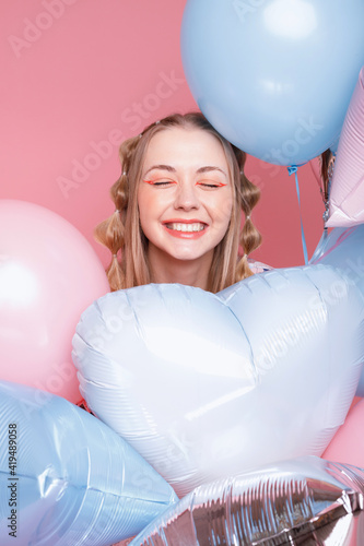 Positive woman in balloons on a pink background