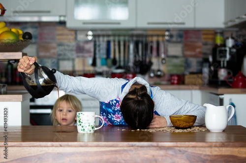 Tired mother, trying to pour coffee in the morning. Woman lying on kitchen table after sleepless night photo