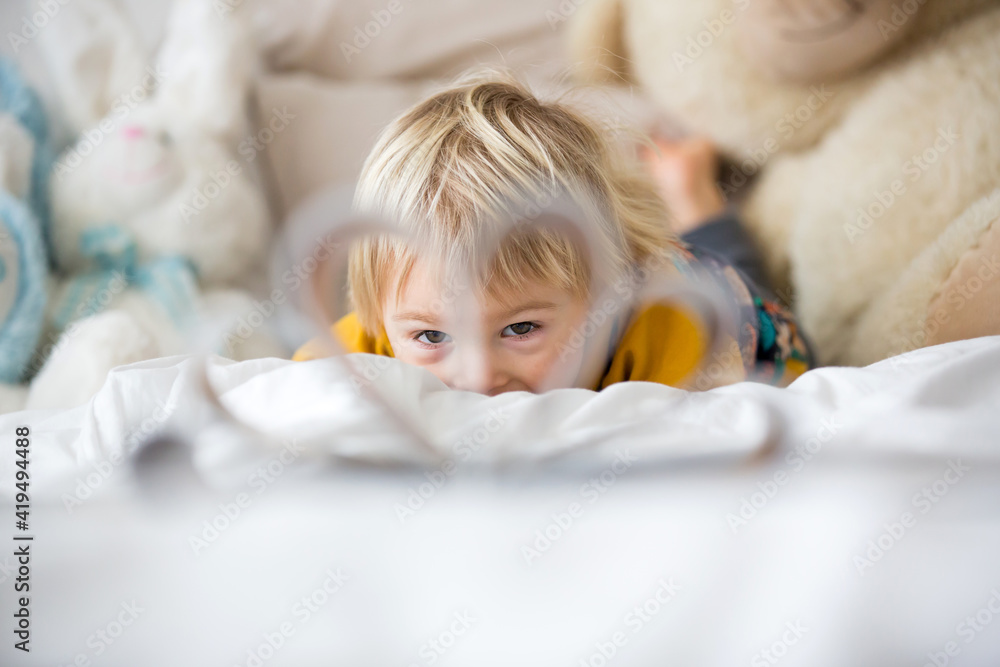Fototapeta premium Beautiful child, toddler boy, reading book and playing with it, creative knowledge shot with book