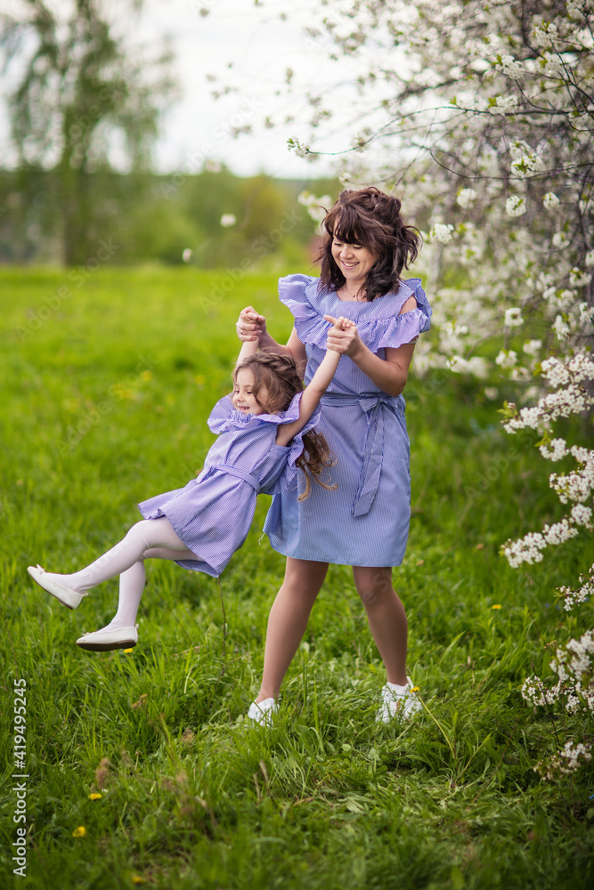 Obraz premium happy mom and daughter in the spring blooming garden playing together