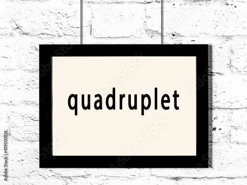 Black frame hanging on white brick wall with inscription quadruplet