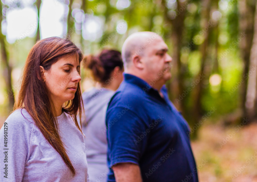 Wellness meditation workshop hispanic adult group relax together with eyes closed in a forest. Breathing in the calm of nature feeling the harmony, health and relieving stress 
