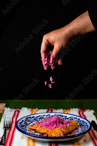 chef serving onion over the cochinita pibil tacos
