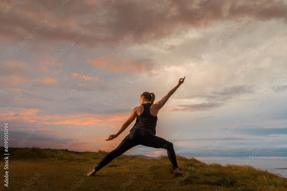 Woman in sportswear in yoga pose in front of the sea at sunset. Woman in sportswear in yoga pose in front of the sea at sunset.