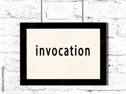 Black frame hanging on white brick wall with inscription invocation