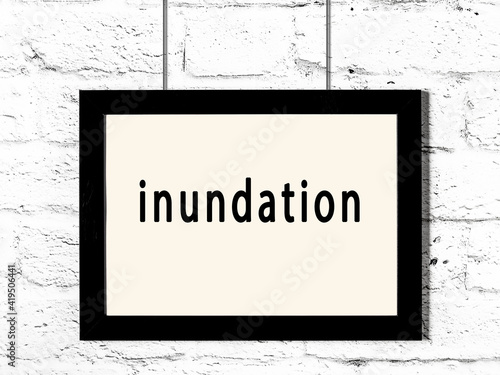 Fotografia Black frame hanging on white brick wall with inscription inundation