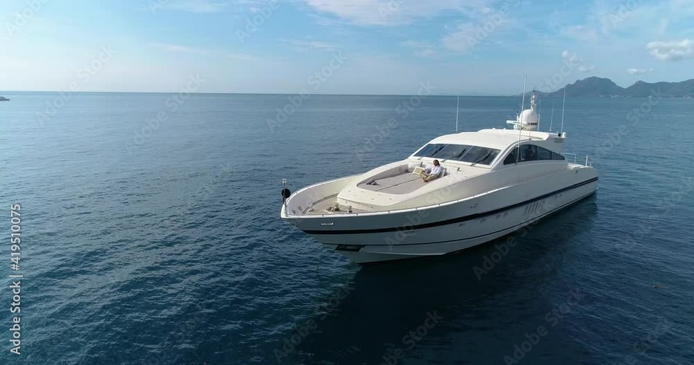 Aerial shot of a man on a boat sailing in the Mediterranean Sea. The man is lying down in the front of the boat Aerial shot of a man on a boat sailing in the Mediterranean Sea. The man is lying down in the front of the boat