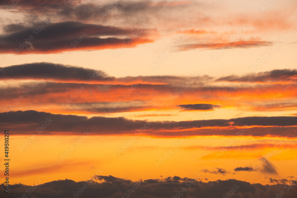 Dramatic sunset landscape with puffy clouds lit by orange setting sun and blue sky. Dramatic sunset landscape with puffy clouds lit by orange setting sun and blue sky.