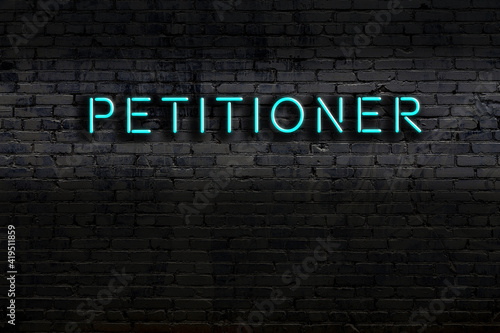 Neon sign. Word petitioner against brick wall. Night view photo