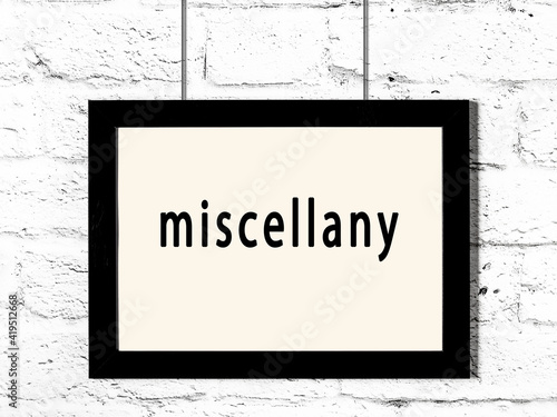 Black frame hanging on white brick wall with inscription miscellany
