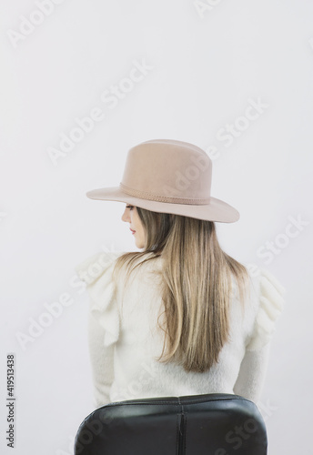 girl in a white sweater posing in a felt hat on a light background © Антон Фрунзе