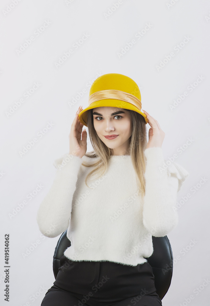 girl in a white sweater posing in a felt hat on a light background girl in a white sweater posing in a felt hat on a light background